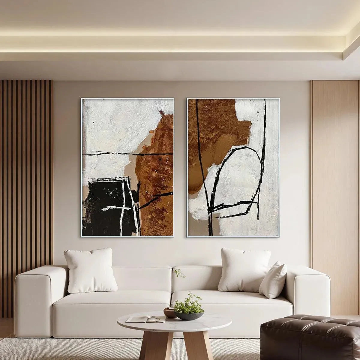 Two vertical brown and white abstract paintings with black lines and texture, in silver frames, displayed above a sofa.
