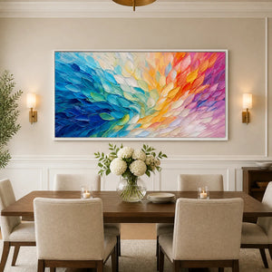 Colorful wing abstract wall art with feather-like texture in blue, orange, and pink tones in a white frame displayed in a refined dining room.