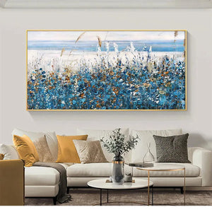 Blue Dunes coastal painting with blue wildflowers in gold frame, displayed above a gray sofa in a contemporary living room.