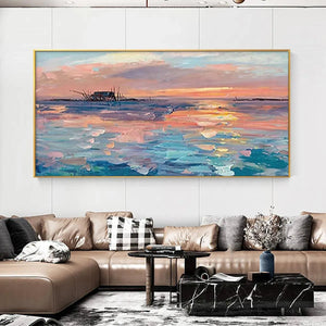 Dusk Reflections panoramic coastal sunset painting, shipwreck, gold frame, above beige sofa in contemporary living room.