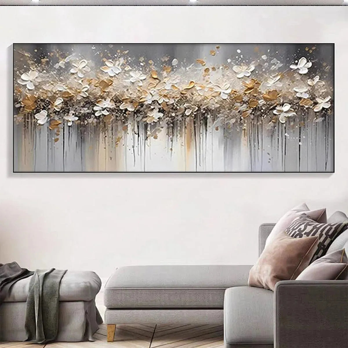 GOLDEN DRIFT: Textured white and gold abstract floral painting with dripping effects above grey sofa in living room.