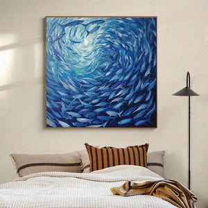 Dynamic 'Oceanic Whirl' blue fish painting in gold frame, mounted above a headboard in a modern bedroom.