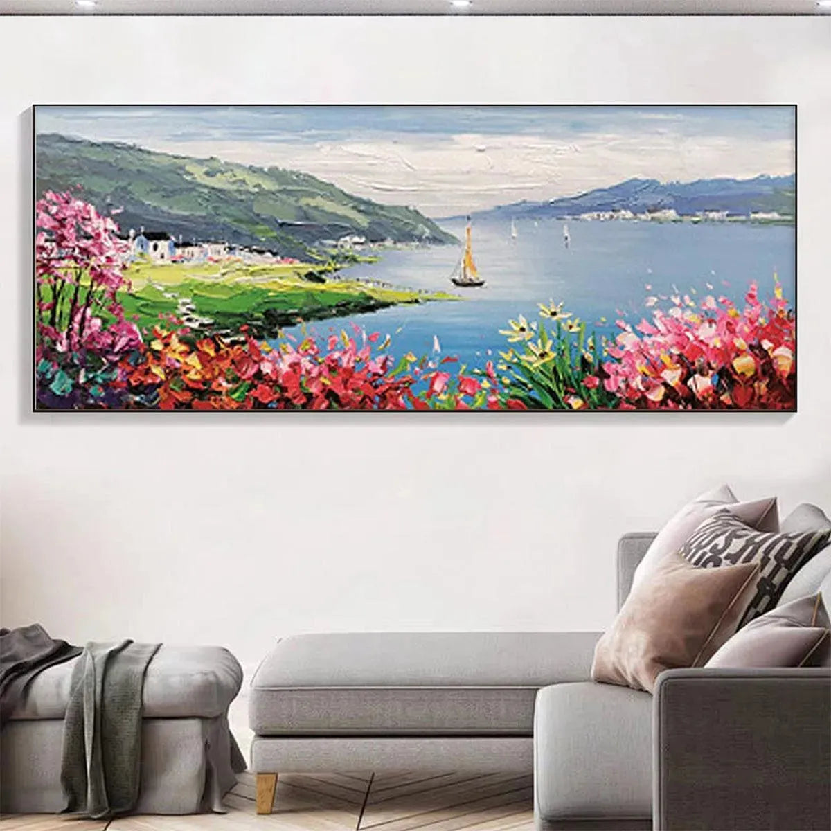 Seaside Charm coastal painting with vibrant flowers & sailboats, above a gray sofa in a modern living room.