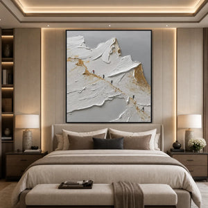 Textured abstract mountain impasto oil painting in white, gold and gray above a beige bed