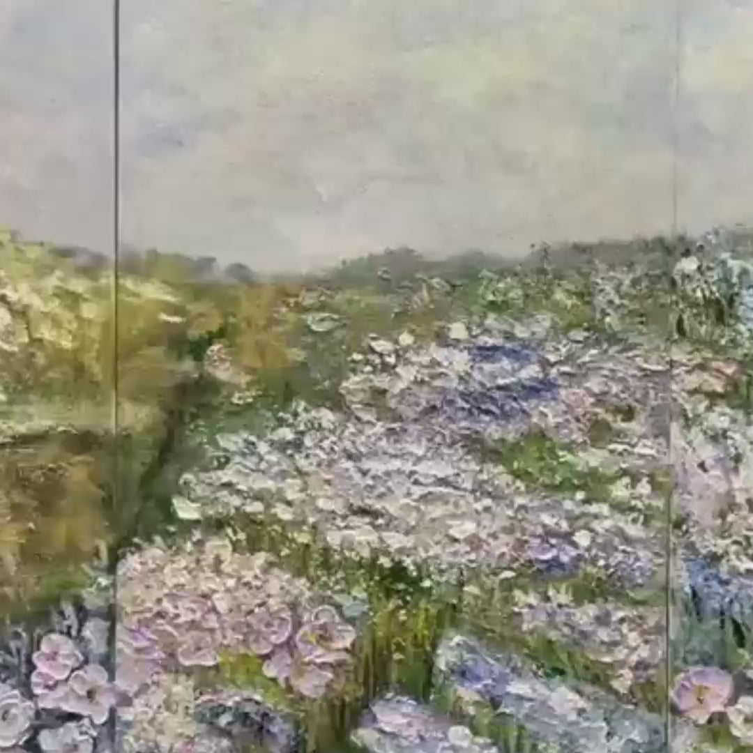 Triptych impressionist wildflower field paintings above cream sofa, muted palette.